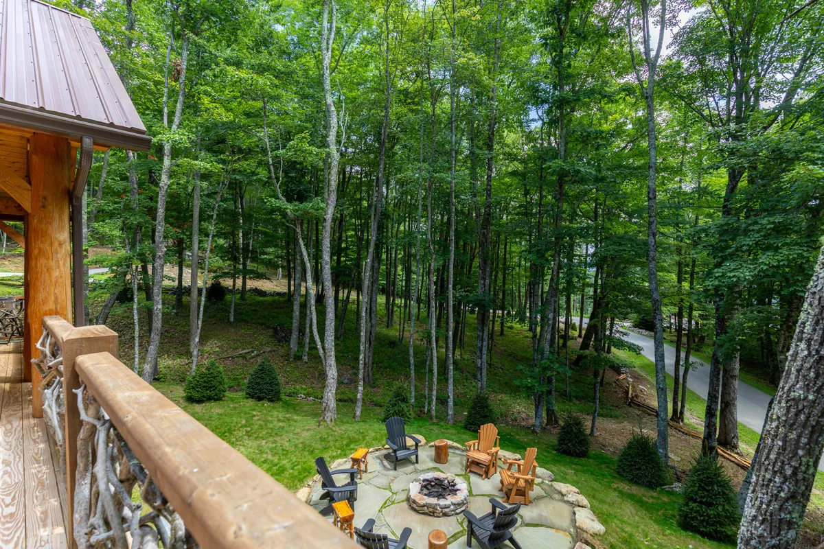 This image features a cozy fire pit surrounded by comfortable seating and nestled among tall trees. The natural setting invites guests to gather in the evening, share stories, and enjoy the tranquility of the forest. The warm glow of the fire contrasts beautifully with the green surroundings, creating an inviting communal space.